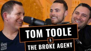 Three smiling men in a podcast studio with microphones and a bold orange sign reading 'Tom Toole & The Broke Agent.'