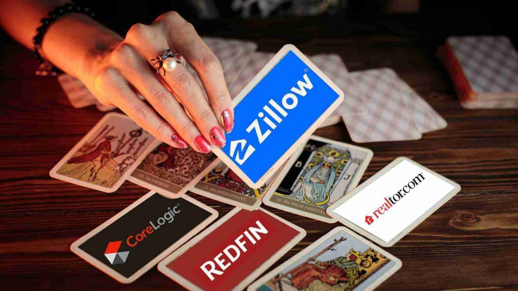 Hand with manicured nails and a ring places a blue Zillow card among scattered real estate brand cards on a wooden table surface.
