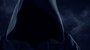 Hooded silhouette with face hidden against a dark cloudy backdrop, creating a mysterious mood.