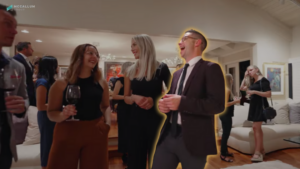 Group of professionals at a social event, two women smiling with wine glasses, and a man in a suit dancing in the foreground.