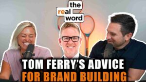 Podcast cover showing three smiling hosts around microphones with a 'the real word' logo, and the title 'Tom Ferry's Advice for Brand Building'
