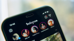 Close-up of a smartphone screen displaying the Instagram app with circular profile icons and the word 'Instagram' at the top.