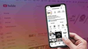 Hand holding a smartphone displaying BAM's YouTube profile with video thumbnails, over a pink gradient YouTube background.