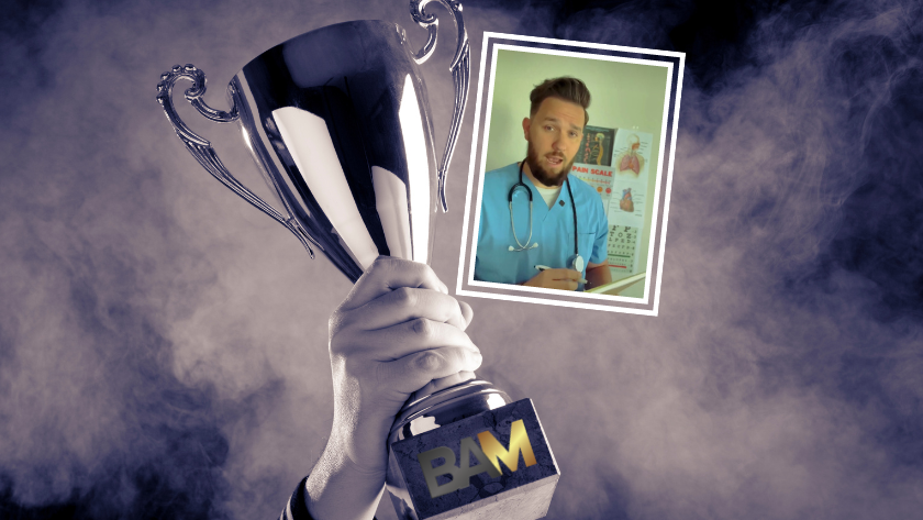 A hand raises a large trophy with a framed photo of a doctor attached, against a smoky blue background.