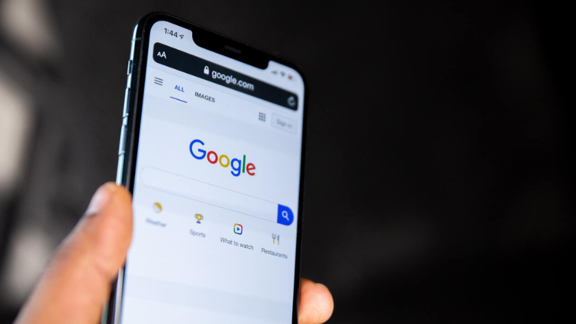 Hand holding a smartphone showing the Google homepage on a browser screen