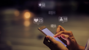 Hands holding a smartphone with floating social notifications above (likes, messages, followers, mentions).