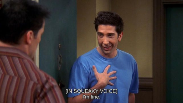 Two men in a hallway; man in a blue shirt touches his chest while saying, 'I'm fine' (squeaky voice).