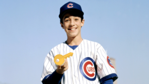 Smiling boy in Cubs uniform holds a large gold key toward the camera.