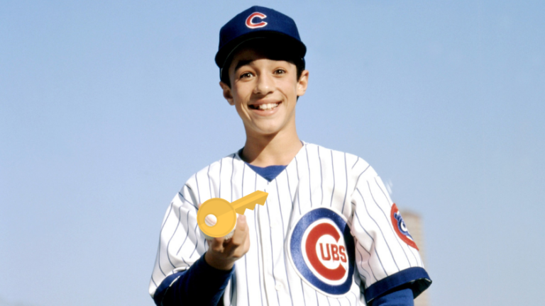 Smiling boy in Cubs uniform holds a large gold key toward the camera.