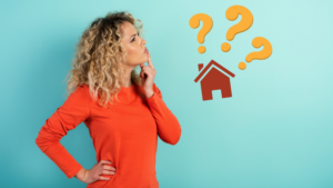 Woman in an orange sweater looks up and rests a hand on her chin, with a house icon and yellow question marks suggesting housing questions.