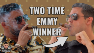 Two men in sunglasses smoke cigars as bold text reads 'Two Time Emmy Winner' with a right-pointing arrow.