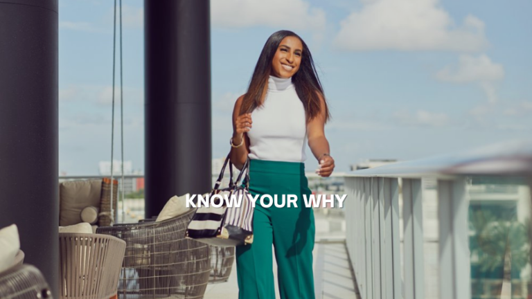 Confident woman on a rooftop terrace with a striped bag, wearing a white sleeveless top and green pants; overlay text reads KNOW YOUR WHY.