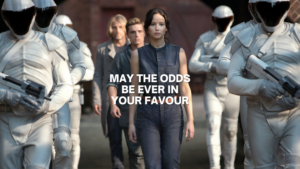 Central woman leads a line of people flanked by white-armored soldiers; bold text reads 'May the odds be ever in your favour'.