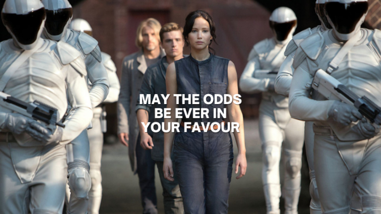 Central woman leads a line of people flanked by white-armored soldiers; bold text reads 'May the odds be ever in your favour'.