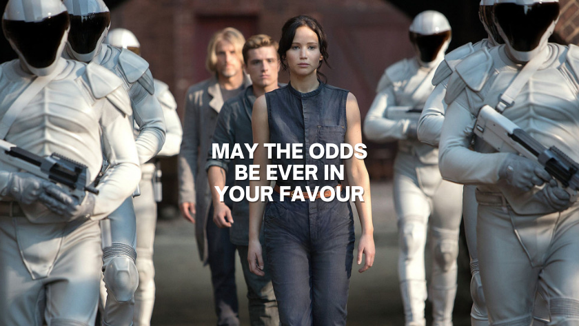 Central woman leads a line of people flanked by white-armored soldiers; bold text reads 'May the odds be ever in your favour'.