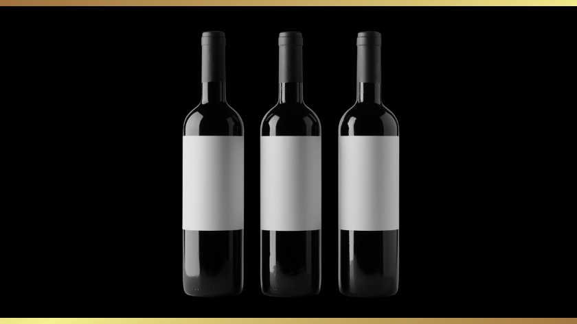 Three dark wine bottles with blank white labels lined up on a black background inside a gold-bordered frame