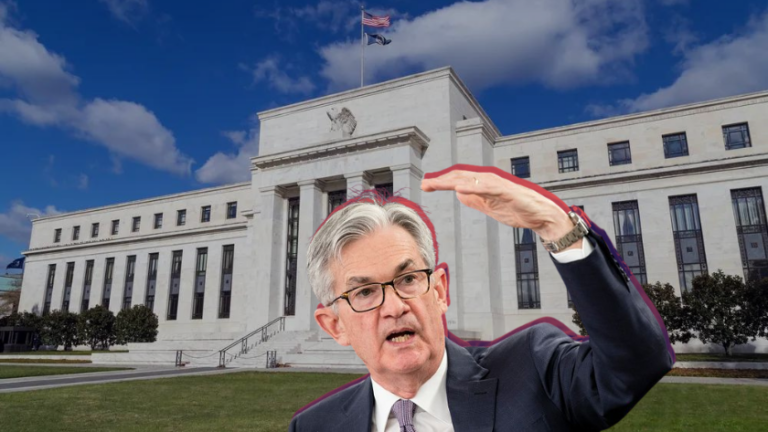 Older man in a suit and glasses stands in front of a white government building, raising one arm as if framing something.