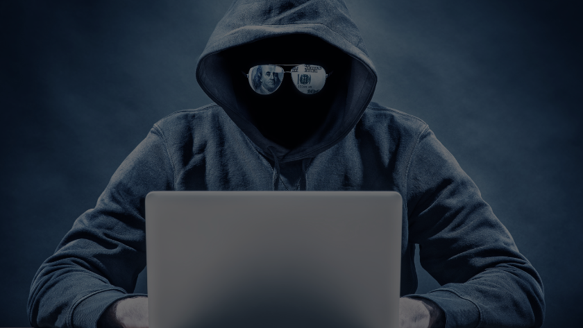 Hooded figure typing on a laptop, face obscured, sunglasses reflecting money in a dark blue scene.