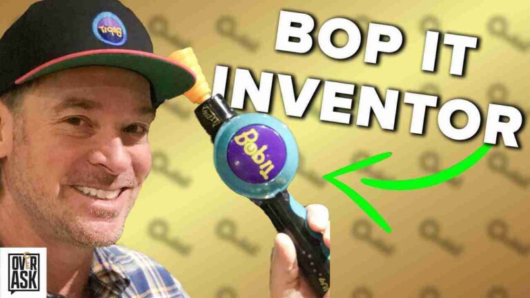 Smiling man in a cap holds a Bop It toy; bold 'BOP IT INVENTOR' text and a neon green arrow highlight the device.