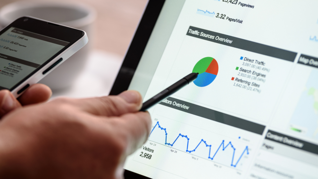 Person using a stylus to view an analytics dashboard with a pie chart and line graph on a tablet/monitor