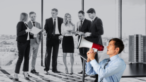Six business professionals in suits discuss documents in a glass-walled office as a man in the foreground speaks into a megaphone to address them.