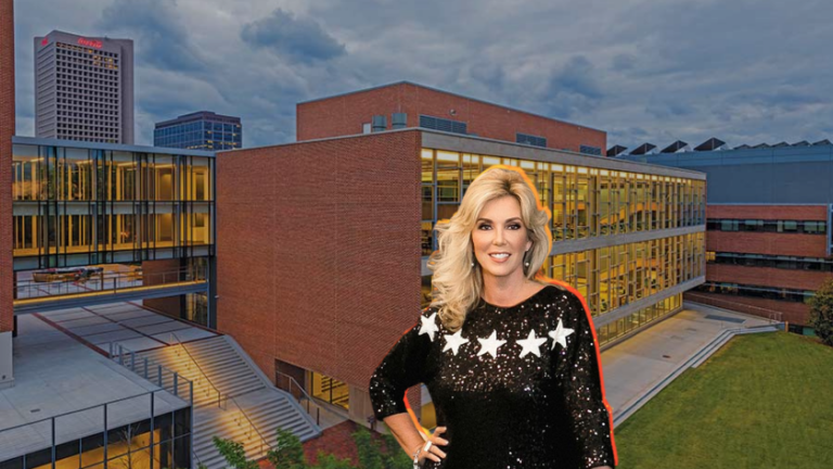 Blonde woman in a black sequined dress with white stars posing outside a modern brick and glass campus building.
