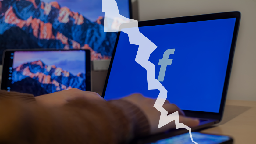 Hand resting on a laptop displaying a blue Facebook screen, with a jagged white crack graphic crossing the image, suggesting a break or outage.