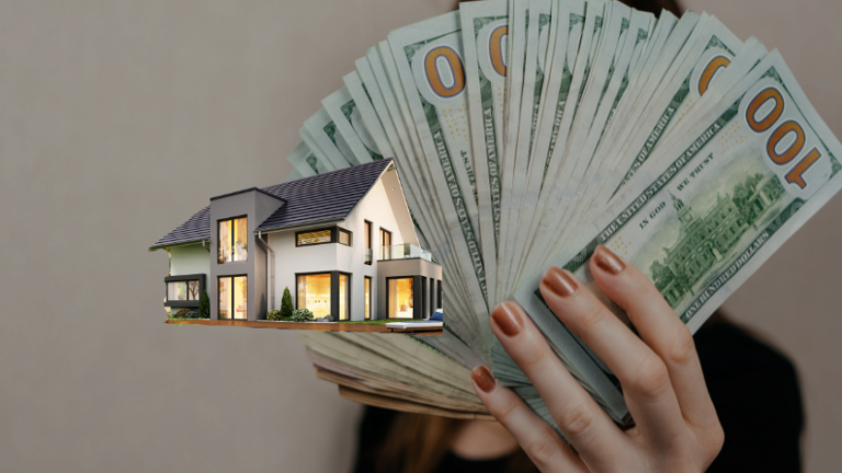 Hand holding a fanned stack of $100 bills beside a miniature modern house model