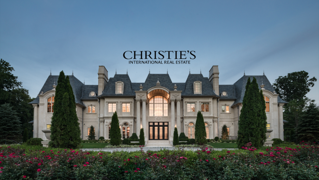 Grand stone mansion with manicured gardens and the Christie’s International Real Estate logo.