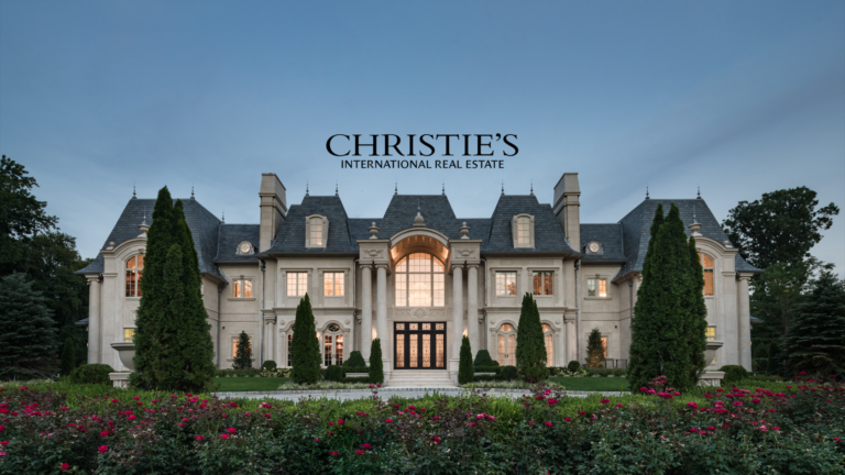 Grand stone mansion with manicured gardens and the Christie’s International Real Estate logo.