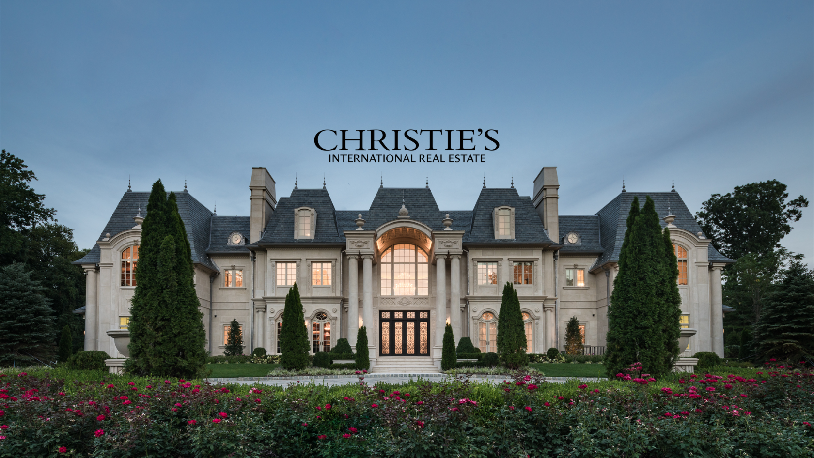 Grand stone mansion with manicured gardens and the Christie’s International Real Estate logo.