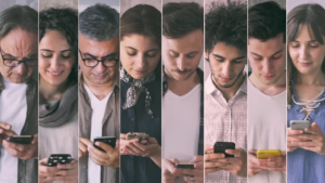 Eight diverse people standing in a row, each focused on a smartphone, illustrating group mobile device use.