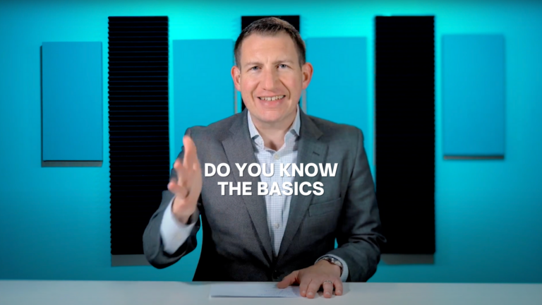 Smiling man in a gray suit speaks at a desk in a blue studio; bold caption reads 'DO YOU KNOW THE BASICS'.