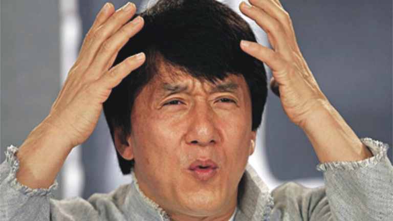 Man with short black hair holds his head with both hands, a distressed or frustrated expression on his face.