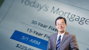 Professional in a suit stands in front of a mortgage document showing 30-year fixed, 15-year fixed, and a blue 5/1 ARM option.