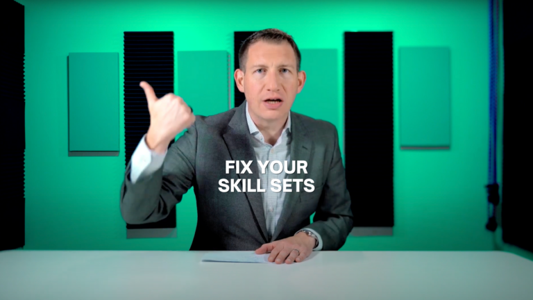 Man in a gray suit sits at a white desk in a green studio, gesturing with his left hand while a note rests on the desk; overlay reads 'FIX YOUR SKILL SETS'.
