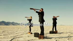 Three businesspeople in suits on wooden boxes in a desert, looking through telescopes, with a Fannie Mae logo overlaid.