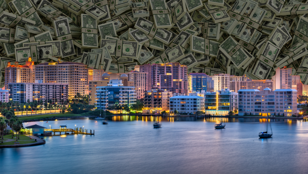 City waterfront with illuminated buildings at dusk and boats on calm water, dollars filling the sky to symbolize wealth and real estate