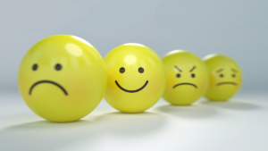 Four glossy yellow emoji balls in a row showing different emotions: sad, happy, angry, and worried.