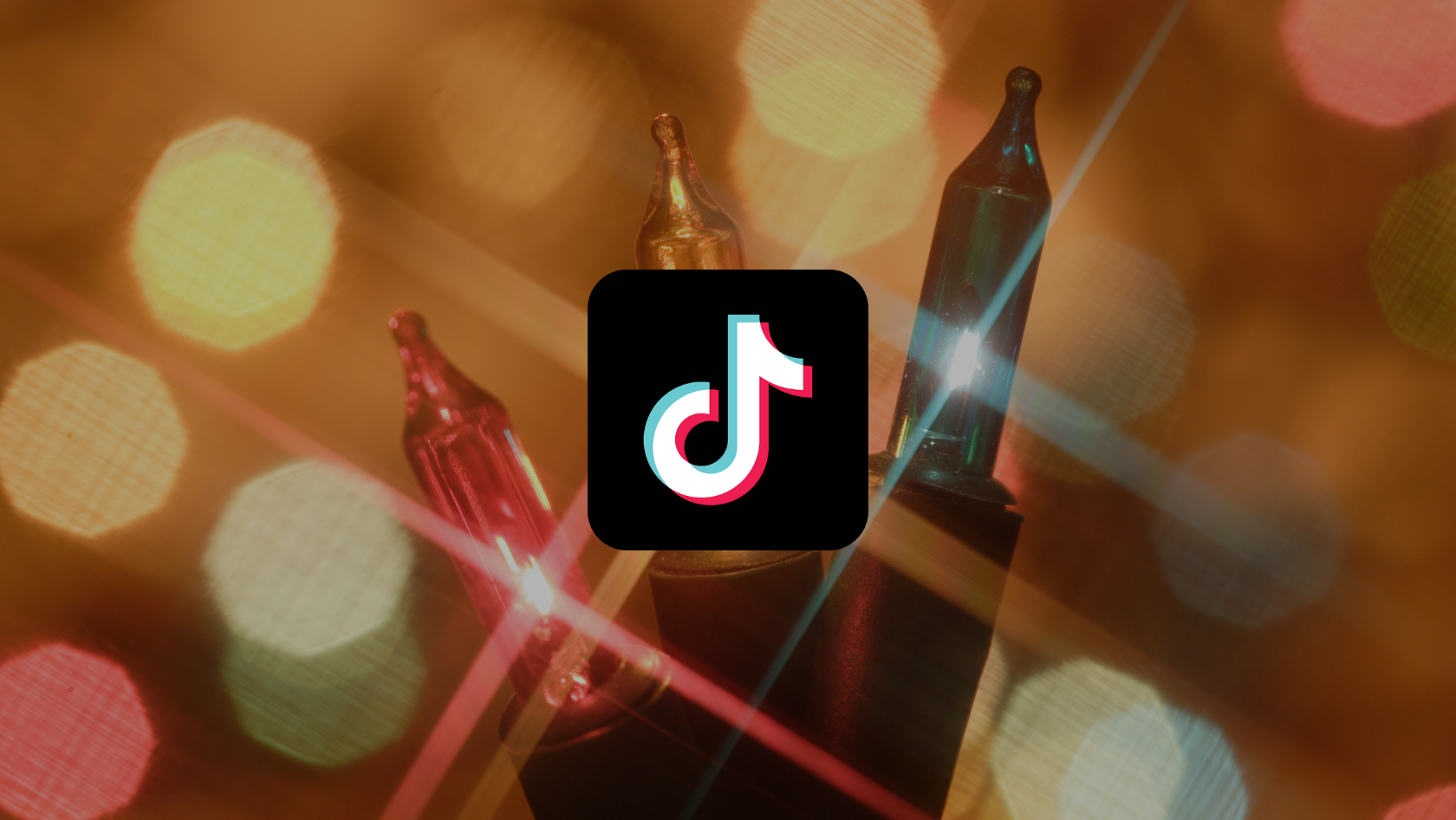 TikTok app icon centered on a black rounded square over a warm bokeh background of lights.