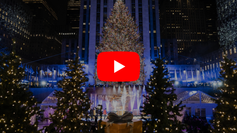 Nighttime view of a large illuminated Christmas tree in a city plaza, with fountains and festive lights, overlaid by a large YouTube play button (video thumbnail).