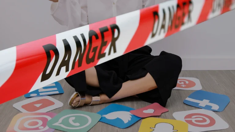 Person sitting on the floor behind red danger tape, surrounded by social media icons (YouTube, Instagram, Facebook, Twitter, Snapchat).