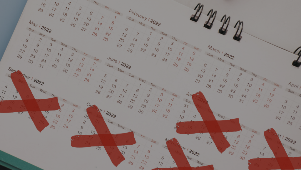 Spiral-bound desk calendar open to 2022 with several red X marks crossing out dates.