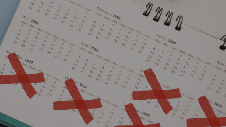 Spiral-bound desk calendar open to 2022 with several red X marks crossing out dates.