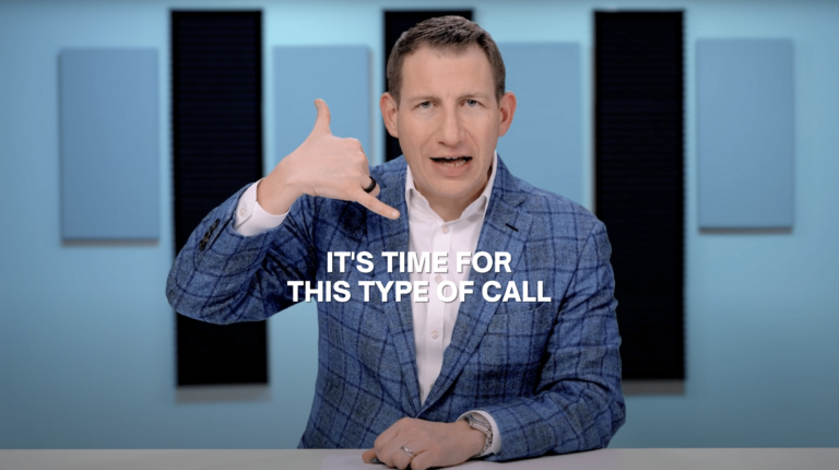 Man in a blue plaid blazer sits at a desk, making a phone gesture with his hand as the caption reads, 'It's time for this type of call'