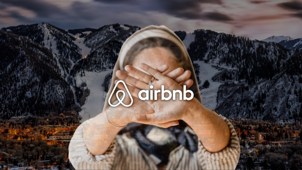 Person in a hoodie covers their face with hands; an Airbnb logo overlays the scene of a snowy mountain town in the background (privacy/anonymous theme).