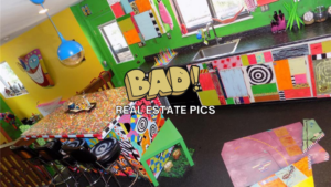 Bright, eclectic kitchen with multicolored patchwork cabinets, a colorful patterned island, and neon yellow wall; overlay text reads 'BAD! REAL ESTATE PICS'.