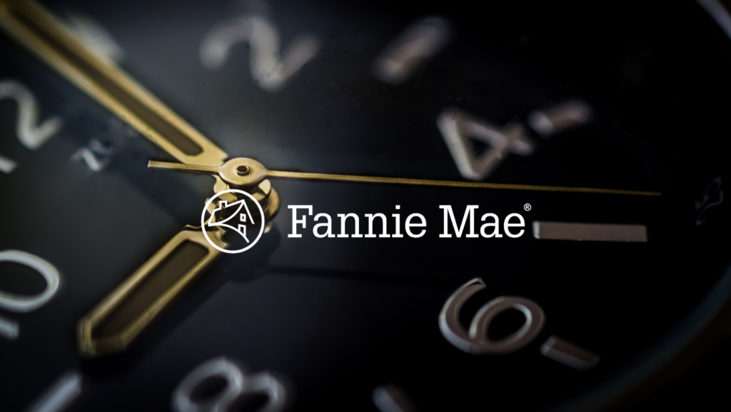 Close-up of a clock face with gold hands and a Fannie Mae logo watermark, suggesting housing finance timing.