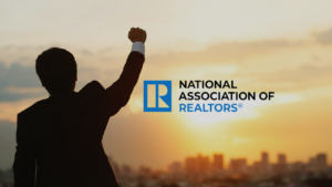 Silhouette of a businessperson raising a clenched fist at sunset beside the National Association of Realtors logo.