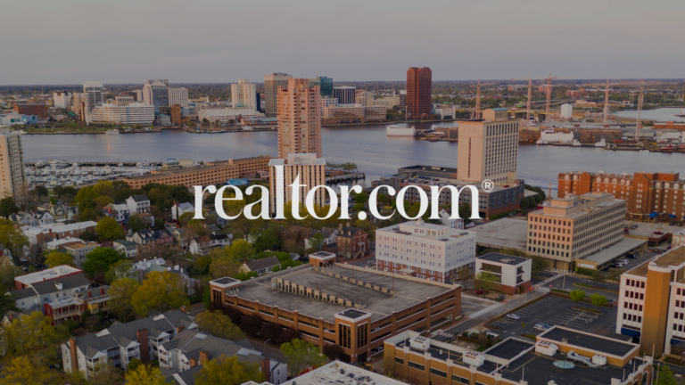 Aerial cityscape over a river with tall office buildings and a marina; realtor.com watermark across the center.